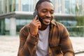 African american man talking on smartphone on street in city outdoor. Man with cell phone chatting with friends. Smiling Royalty Free Stock Photo