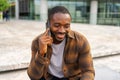 African american man talking on smartphone on street in city outdoor. Man with cell phone chatting with friends. Smiling Royalty Free Stock Photo