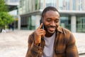 African american man talking on smartphone on street in city outdoor. Man with cell phone chatting with friends. Smiling Royalty Free Stock Photo