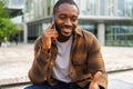 African american man talking on smartphone on street in city outdoor. Man with cell phone chatting with friends. Smiling Royalty Free Stock Photo