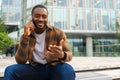 African american man talking on smartphone on street in city outdoor. Man with cell phone chatting with friends. Smiling Royalty Free Stock Photo