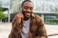 African american man talking on smartphone on street in city outdoor. Man with cell phone chatting with friends. Smiling Royalty Free Stock Photo