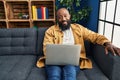 African american man using laptop at home sitting on the sofa looking positive and happy standing and smiling with a confident Royalty Free Stock Photo