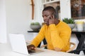African american man using laptop at home and talking on smartphone Royalty Free Stock Photo