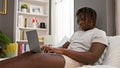 African american man using laptop lying on bed at bedroom Royalty Free Stock Photo
