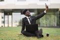 African-American man using laptop outdoors, sitting on the grass near office Royalty Free Stock Photo