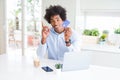 African American man using laptop and shopping online with credit card surprised with an idea or question pointing finger with Royalty Free Stock Photo