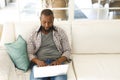 African american man using laptop sitting on couch in living room Royalty Free Stock Photo