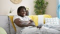 African american man using laptop sitting on sofa with arms crossed gesture at home Royalty Free Stock Photo