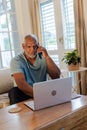 African American man using laptop and talking on smartphone at home Royalty Free Stock Photo