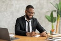 African American man using laptop writing in notebook Royalty Free Stock Photo