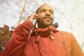 African American man using mobile phone in the park. Young happy smiling urban hipster man wearing informal clothes and Royalty Free Stock Photo