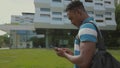 African American Man using smart phone walking in city. Handsome young man with backpack communicating on smartphone Royalty Free Stock Photo