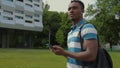 African American Man using smart phone walking in city. Handsome young man with backpack communicating on smartphone Royalty Free Stock Photo