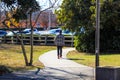 An African American man walking on a smooth winding footpath in the par surrounded by lush green and autumn colored trees