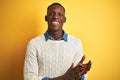 African american man wearing denim shirt and white sweater over isolated yellow background clapping and applauding happy and Royalty Free Stock Photo