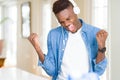 African american man wearing headphones listening to music very happy and excited doing winner gesture with arms raised, smiling Royalty Free Stock Photo