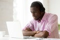 African-american man wearing headphones using laptop looking at Royalty Free Stock Photo