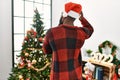 African american man wearing santa claus hat standing by christmas tree backwards thinking about doubt with hand on head Royalty Free Stock Photo