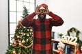 African american man wearing santa claus hat standing by christmas tree doing ok gesture like binoculars sticking tongue out, eyes Royalty Free Stock Photo