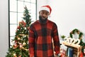 African american man wearing santa claus hat standing by christmas tree looking sleepy and tired, exhausted for fatigue and Royalty Free Stock Photo