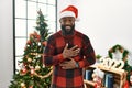 African american man wearing santa claus hat standing by christmas tree smiling and laughing hard out loud because funny crazy Royalty Free Stock Photo