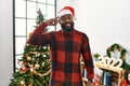 African american man wearing santa claus hat standing by christmas tree smiling pointing to head with one finger, great idea or Royalty Free Stock Photo