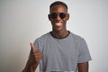 African american man wearing striped t-shirt and sunglasses over isolated white background doing happy thumbs up gesture with hand Royalty Free Stock Photo