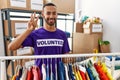 African american man wearing volunteer t shirt at donations stand showing and pointing up with fingers number three while smiling
