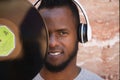 African american man with white headphones holding a vinyl record in his hand and covering part of his face Royalty Free Stock Photo