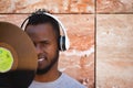 African american man with white headphones holding a vinyl record in his hand and covering part of his face Royalty Free Stock Photo