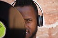 African american man with white headphones holding a vinyl record in his hand and covering part of his face Royalty Free Stock Photo