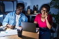 African american man and woman business workers using laptop talking on the smartphone at office