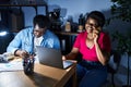 African american man and woman business workers using laptop talking on the smartphone at office