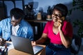 African american man and woman business workers using laptop talking on the smartphone at office