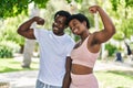 African american man and woman couple doing strong gesture with arms at park Royalty Free Stock Photo