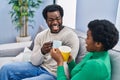 African american man and woman couple drinking coffee sitting on sofa at home Royalty Free Stock Photo