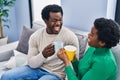 African american man and woman couple drinking coffee sitting on sofa at home Royalty Free Stock Photo