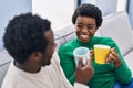 African american man and woman couple drinking coffee sitting on sofa at home Royalty Free Stock Photo