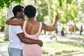 African american man and woman couple hugging each other pointing with finger at park