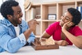 African american man and woman couple playing chess sitting on table at home Royalty Free Stock Photo