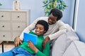 African american man and woman couple using touchpad sitting on sofa at home Royalty Free Stock Photo
