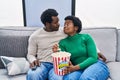 African american man and woman couple watching movie eating popcorn at home Royalty Free Stock Photo