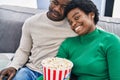 African american man and woman couple watching movie eating popcorn at home Royalty Free Stock Photo