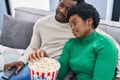 African american man and woman couple watching movie eating popcorn at home Royalty Free Stock Photo