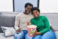 African american man and woman couple watching movie eating popcorn at home Royalty Free Stock Photo