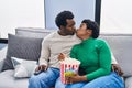 African american man and woman couple watching movie eating popcorn kissing at home Royalty Free Stock Photo