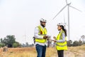 African american man and woman engineers in uniform discuss and use tablet working stand near wind turbines ecological energy