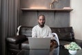 African American man working with laptop computer remote while sitting at sofa in living room. Black guy do freelance Royalty Free Stock Photo