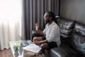 African American man working with laptop computer video calling and conference, remote work while sitting at sofa in Royalty Free Stock Photo